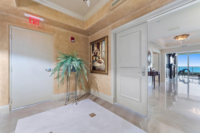 corridor with a raised ceiling, ornamental molding, and a water view