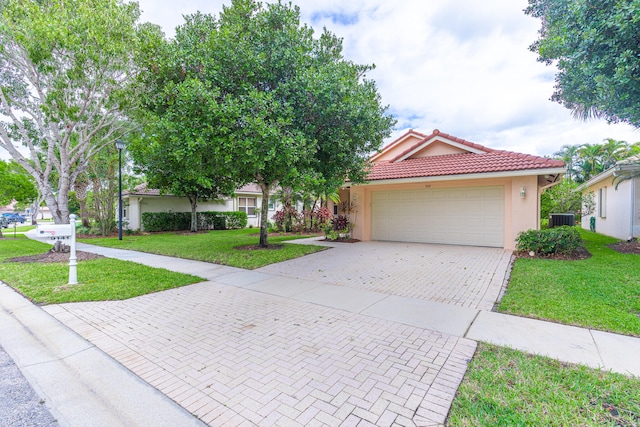 view of front of home with central air condition unit, a front yard, and a garage