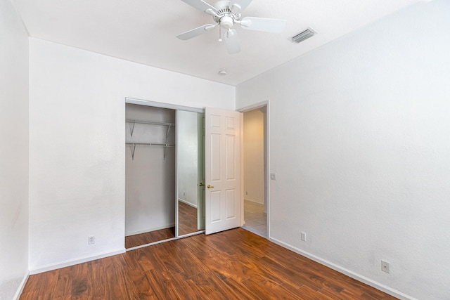 unfurnished bedroom with dark hardwood / wood-style flooring, a closet, and ceiling fan