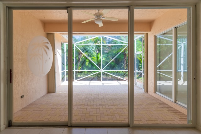 doorway featuring light tile patterned flooring and ceiling fan