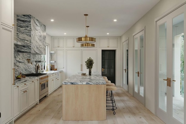 interior space featuring french doors, a healthy amount of sunlight, brick wall, and light hardwood / wood-style flooring