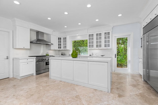 kitchen with white cabinetry, high quality appliances, wall chimney exhaust hood, and ornamental molding