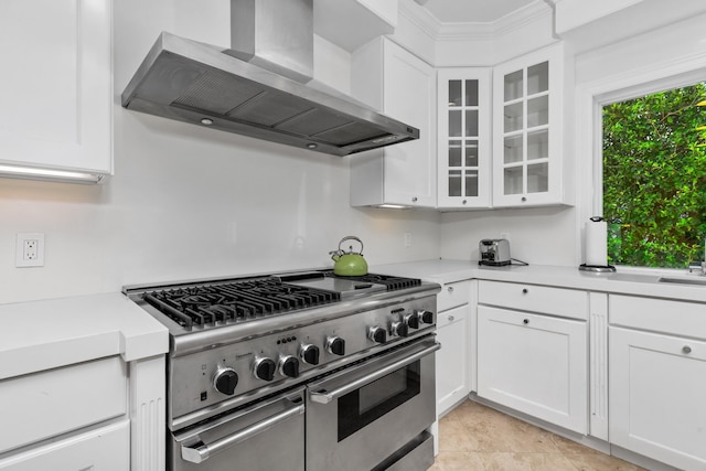 kitchen with white cabinetry, wall chimney range hood, and high end range