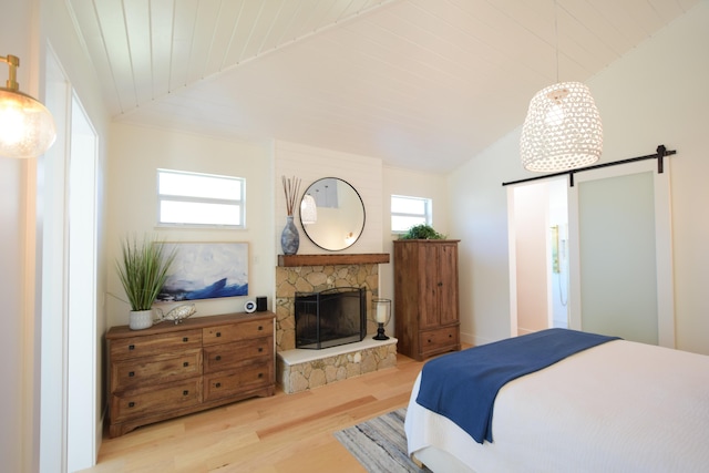 bedroom featuring lofted ceiling, a stone fireplace, light wood-type flooring, and wooden ceiling