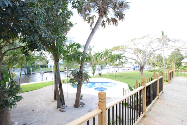 exterior space featuring a lawn, a pool with hot tub, a water view, and a patio