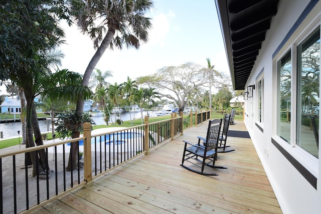 wooden terrace featuring a fenced in pool and a water view