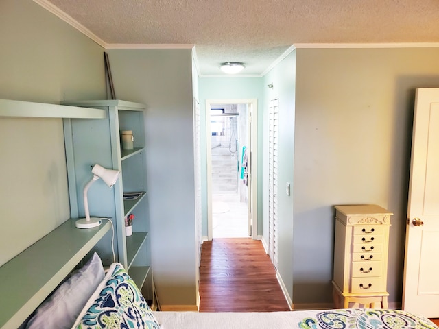 interior space with a textured ceiling, hardwood / wood-style flooring, and ornamental molding