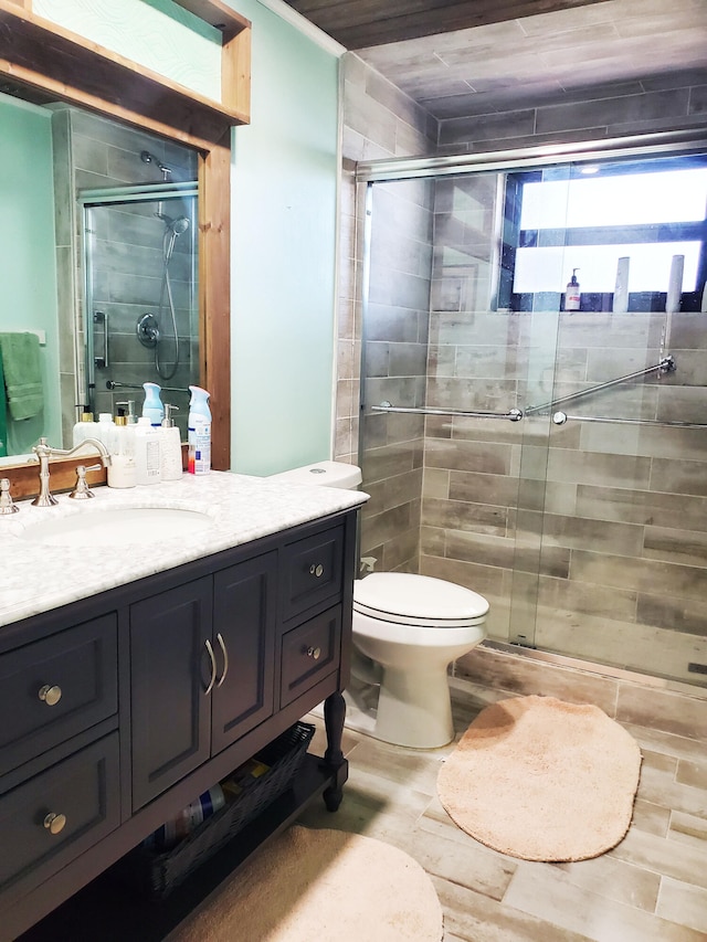 bathroom featuring hardwood / wood-style floors, vanity, toilet, and an enclosed shower