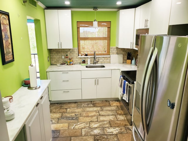 kitchen featuring pendant lighting, white cabinets, stainless steel appliances, and plenty of natural light