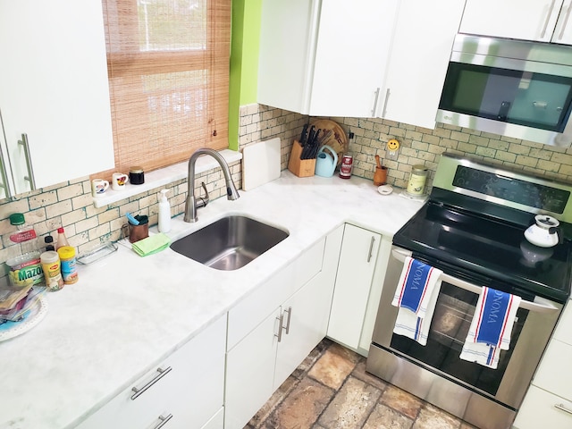 kitchen with white cabinets, backsplash, sink, and appliances with stainless steel finishes