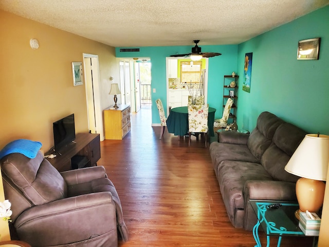 living room featuring a textured ceiling, hardwood / wood-style flooring, and ceiling fan