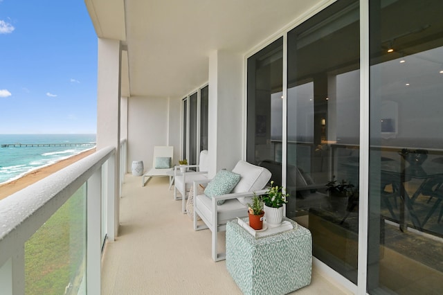 balcony featuring a view of the beach and a water view