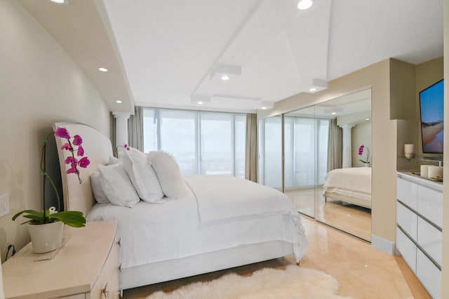 bedroom with ornate columns, expansive windows, and light tile patterned flooring