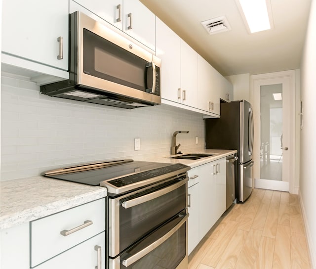 kitchen with sink, white cabinets, stainless steel appliances, and light wood-type flooring