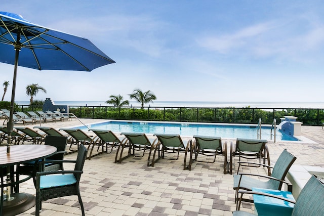 view of pool with a patio and a water view