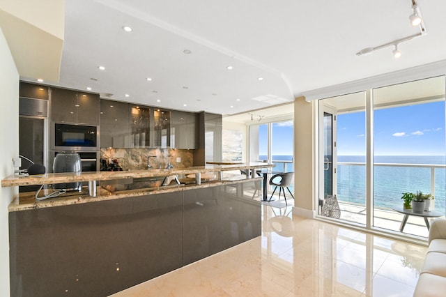 kitchen with a water view, decorative backsplash, built in refrigerator, kitchen peninsula, and stone counters