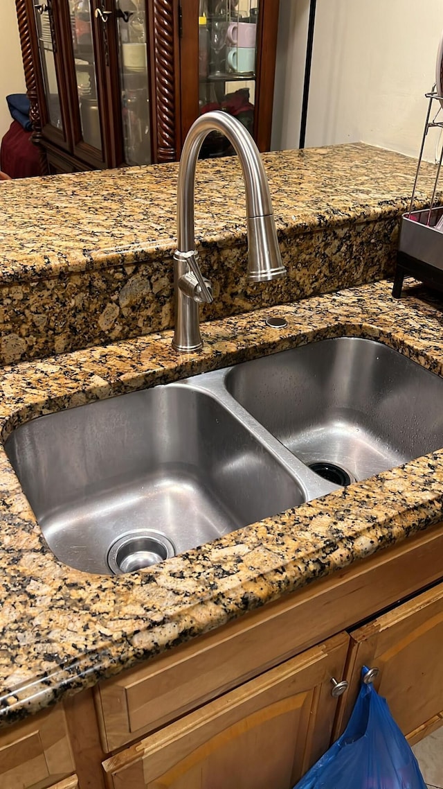 details with glass insert cabinets, a sink, and dark stone countertops