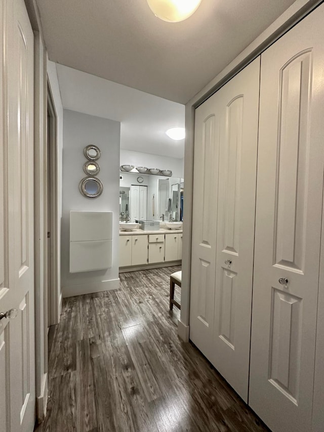 corridor with dark hardwood / wood-style flooring and sink