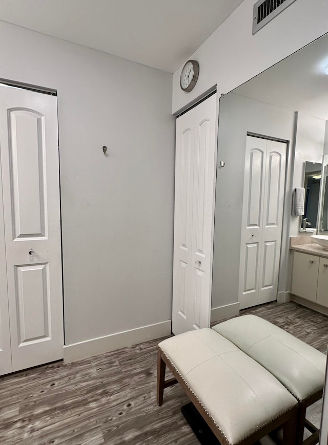 bedroom with dark wood-type flooring and connected bathroom