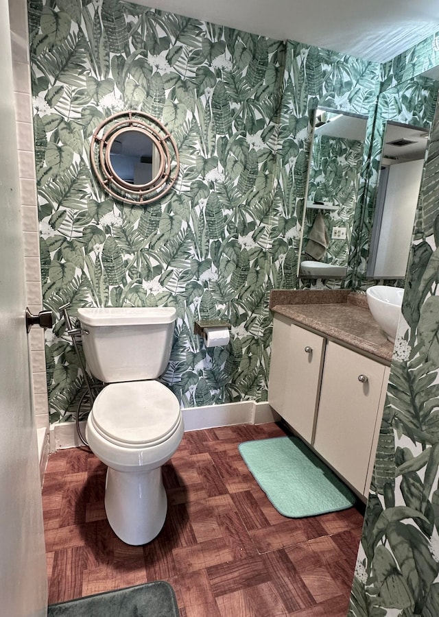 bathroom with parquet flooring, vanity, and toilet