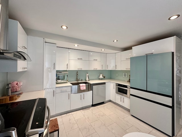 kitchen with wall chimney exhaust hood, white cabinetry, sink, and appliances with stainless steel finishes