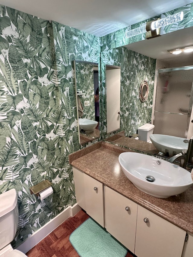 bathroom with vanity, parquet floors, an enclosed shower, and toilet