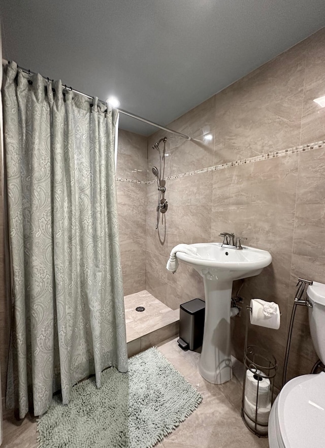 bathroom featuring tile patterned flooring, toilet, tile walls, and walk in shower