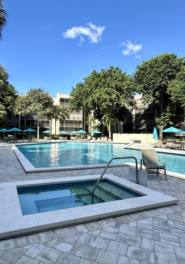 view of swimming pool featuring a patio and a hot tub