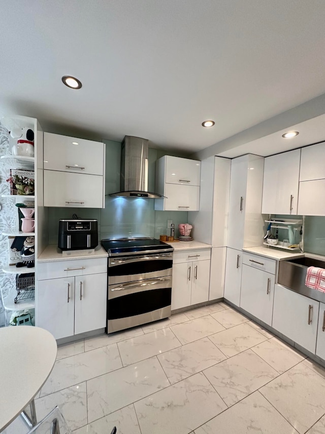 kitchen with stainless steel stove, white cabinetry, wall chimney exhaust hood, and sink