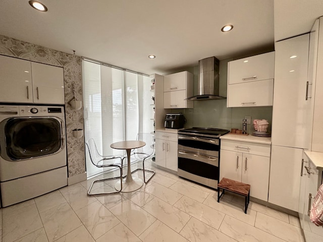 kitchen featuring washer / dryer, stainless steel stove, white cabinetry, and wall chimney exhaust hood