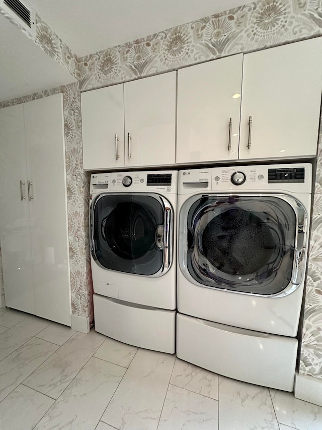 washroom featuring cabinets and separate washer and dryer