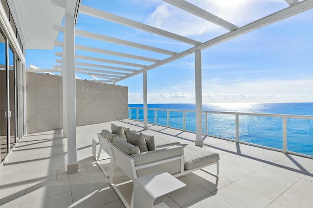 view of patio with a balcony, a water view, outdoor lounge area, and a view of the beach