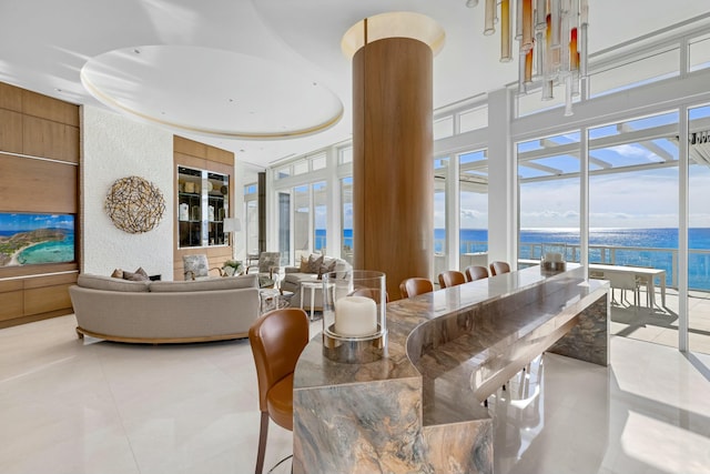 dining space featuring ornate columns, light tile patterned flooring, a water view, and a towering ceiling