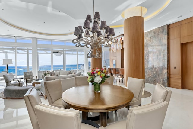 dining area featuring expansive windows, a water view, and a notable chandelier