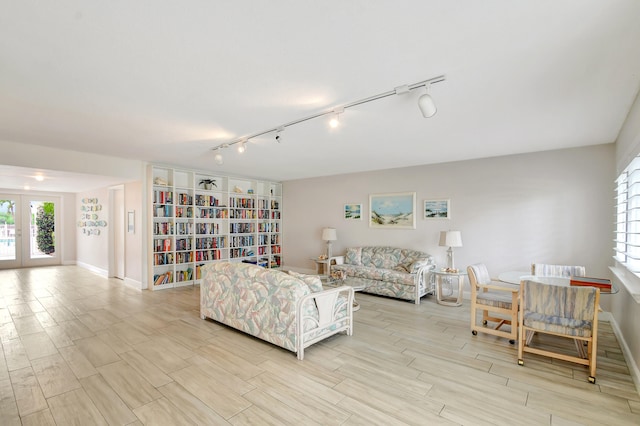 living room featuring french doors, rail lighting, and light hardwood / wood-style floors