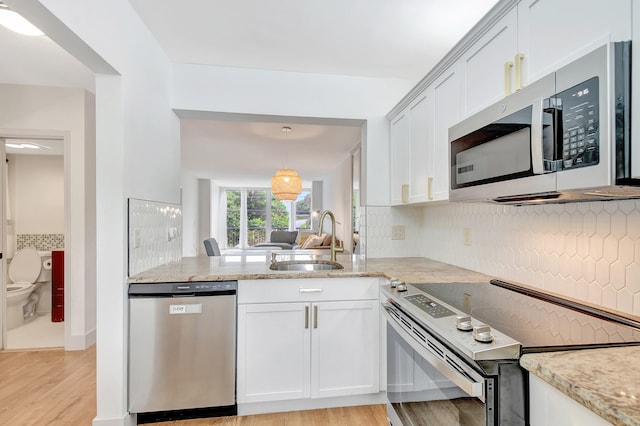 kitchen with sink, light wood-type flooring, appliances with stainless steel finishes, tasteful backsplash, and light stone counters