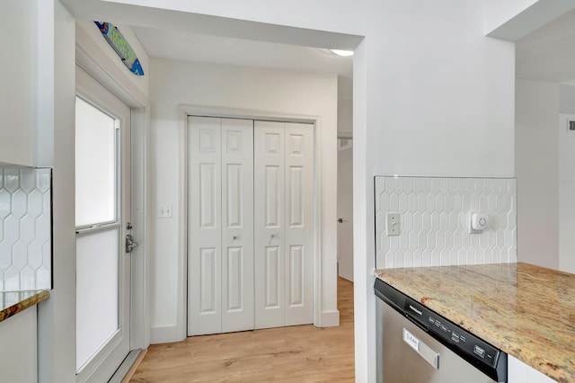 kitchen with dishwasher, light stone counters, backsplash, white cabinets, and light wood-type flooring