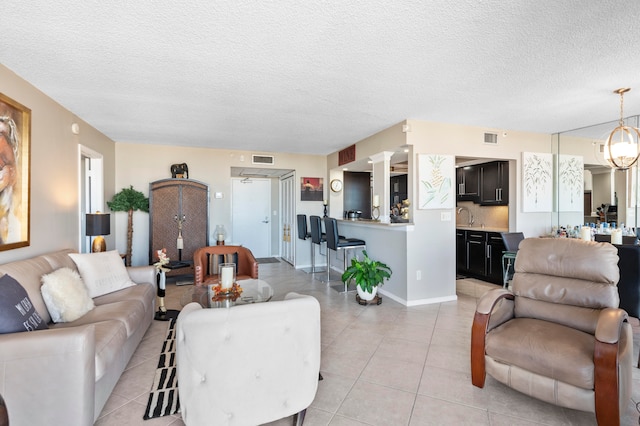 living room with sink, ceiling fan, light tile patterned flooring, and a textured ceiling