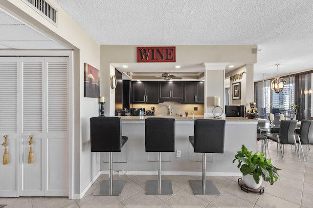 899 Jeffery St Unit 604, Boca Raton, FL 33487 - kitchen featuring a kitchen bar, light countertops, a textured ceiling, and light tile patterned flooring
