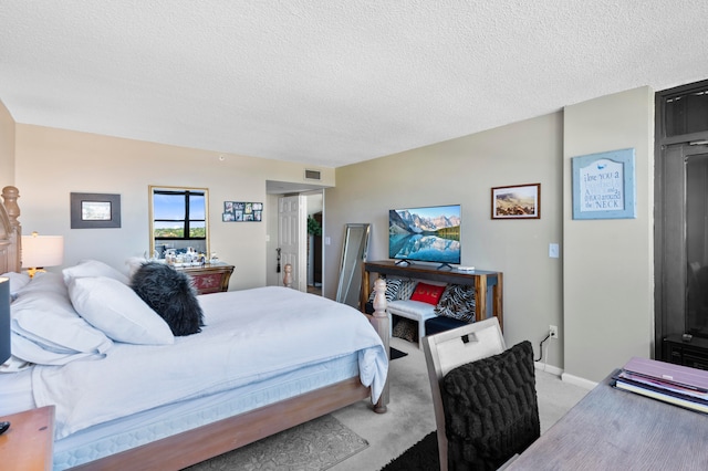 bedroom with light colored carpet and a textured ceiling