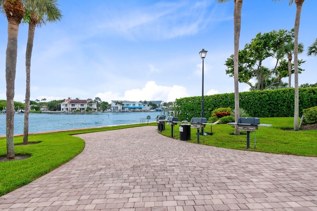 view of property's community with a water view and a lawn