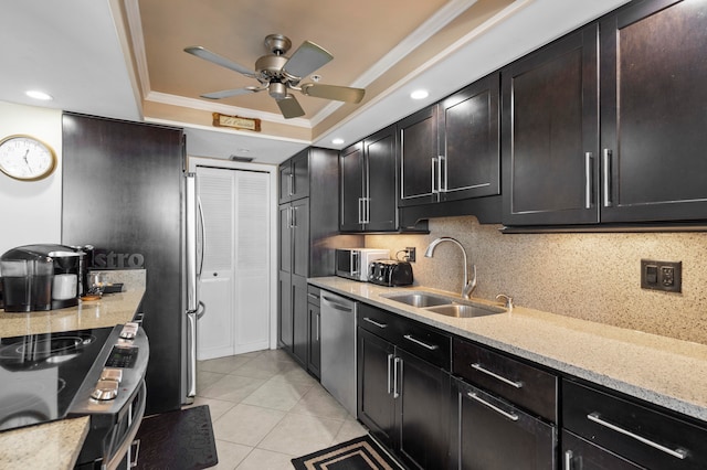 kitchen with ornamental molding, sink, a tray ceiling, light tile patterned flooring, and appliances with stainless steel finishes