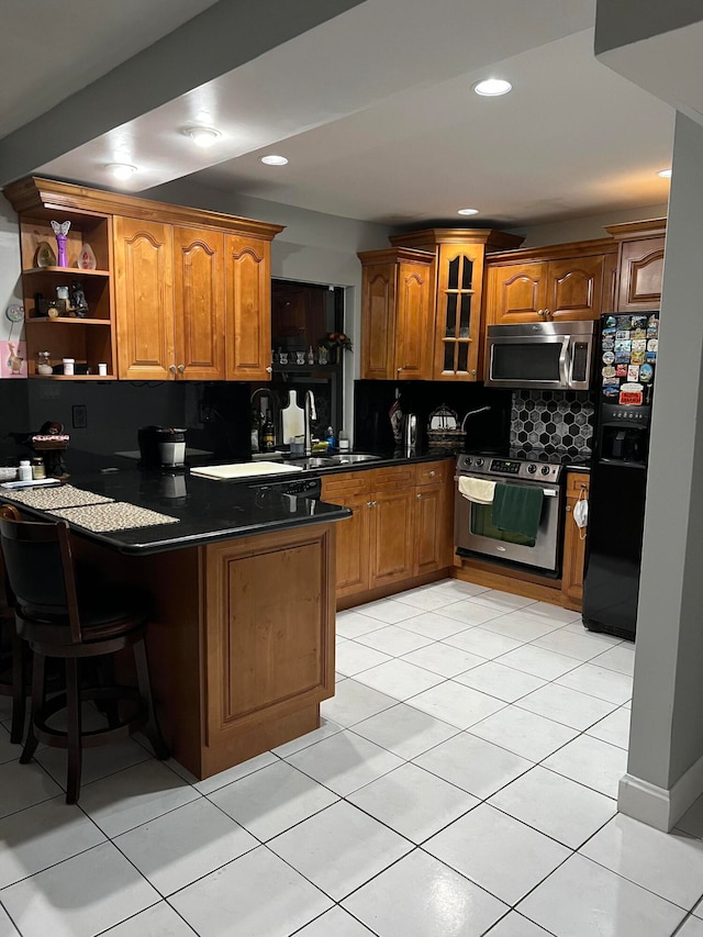 kitchen featuring light tile patterned flooring, kitchen peninsula, appliances with stainless steel finishes, and tasteful backsplash