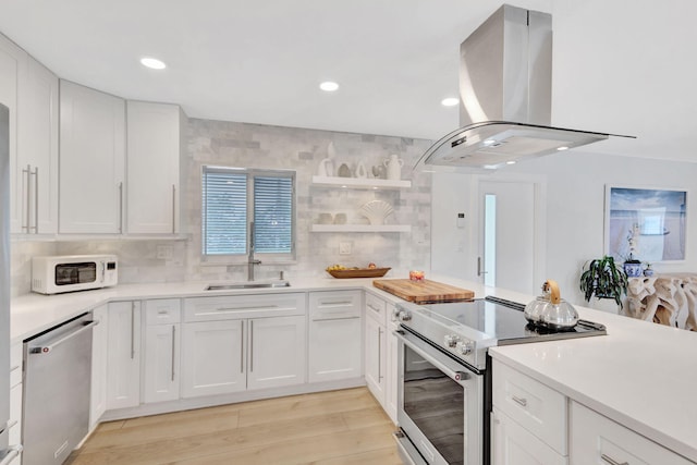 kitchen featuring island range hood, light hardwood / wood-style flooring, white cabinets, and stainless steel appliances