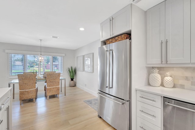 kitchen featuring decorative backsplash, stainless steel appliances, pendant lighting, light hardwood / wood-style floors, and white cabinetry