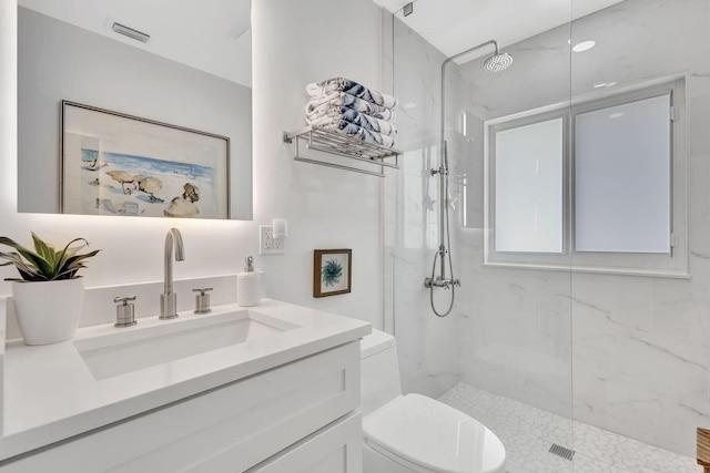 bathroom with a tile shower, vanity, and toilet