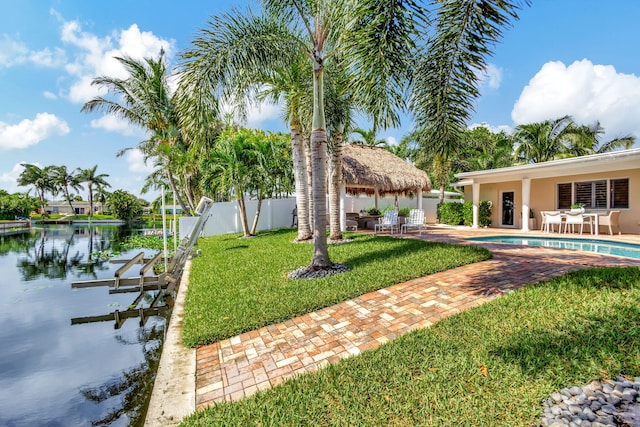 view of yard with a water view, a patio, and a dock