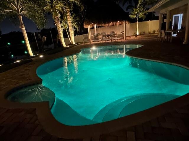 pool at night with a patio area