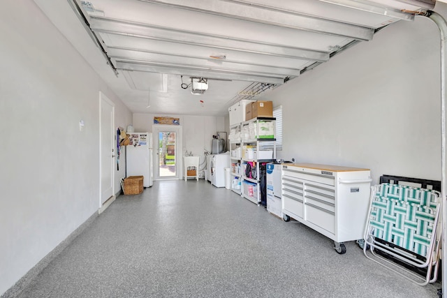 garage featuring independent washer and dryer, white fridge, and a garage door opener