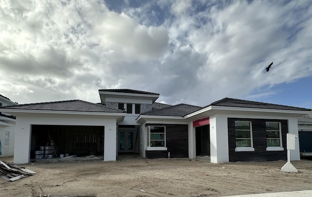 view of front facade with french doors, a garage, and stucco siding